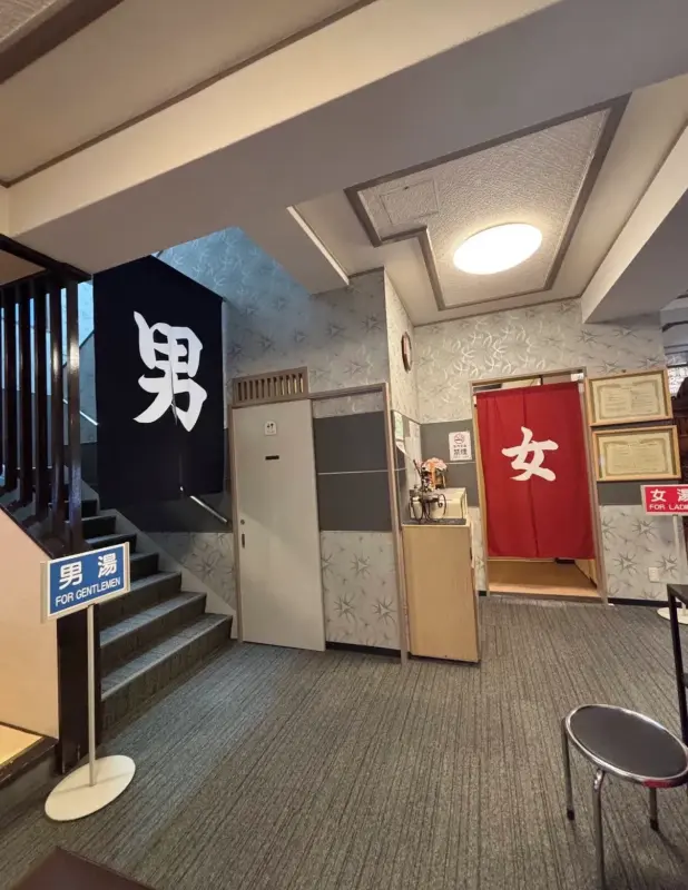 Entrance of a Japanese onsen showing the men’s (男湯) and women’s (女湯) sections with traditional noren curtains.