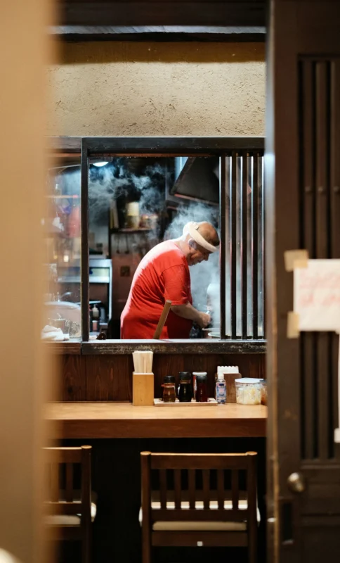 perry-merrity-ii-A0p0tPjO75M-unsplash Japanese izakaya owner cooking behind the counter in a small neighborhood bar