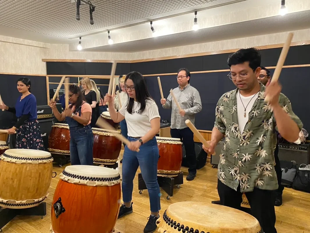 att.aThJIF0171FvSRdqLYbWs2UidMxBCubS6Qc64p_6Opw 2 Foreign travelers learning Japanese taiko drumming in a Tokyo workshop