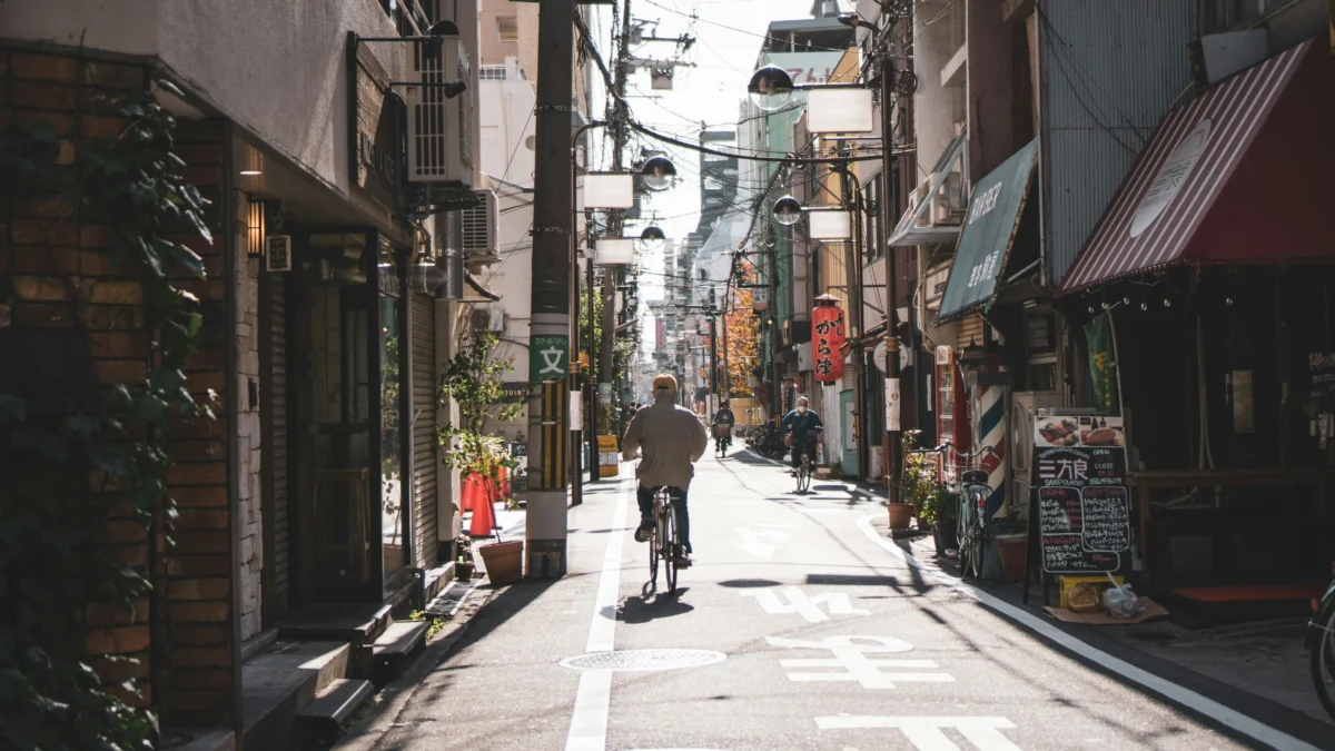emil-karlsson-dY7m7gihd6w-unsplash Quiet local street in Japan with bicycles, small shops, and overhead cables