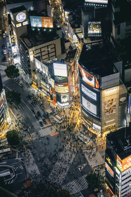 Shibuya Crossing viewed from above at night with pedestrians and city lights