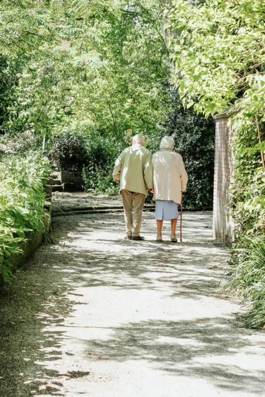 micheile-henderson-PpZasS086os-unsplash Elderly couple walking slowly together along a garden path