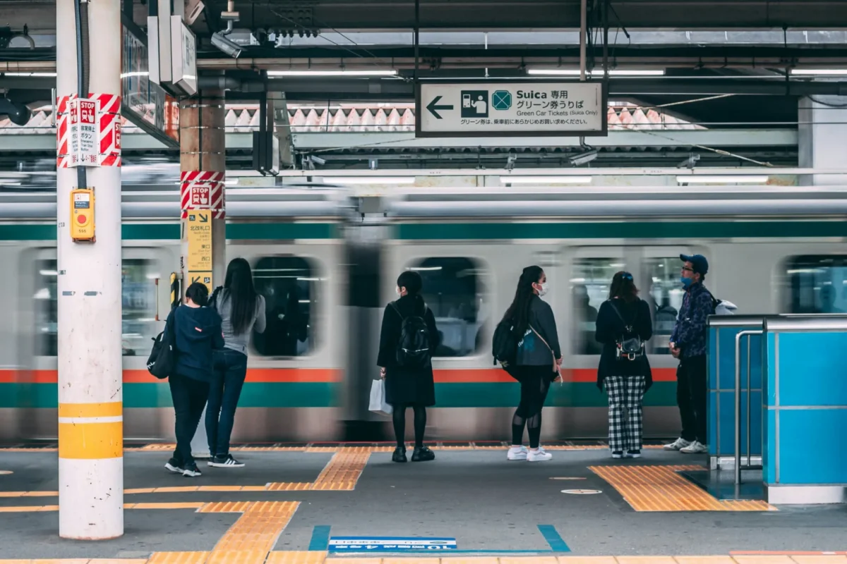 Passengers waiting on a Tokyo train platform as a train passes